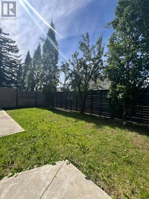 Toronto (East York) triplex for rent - A sunny day in a backyard with a fence and trees.