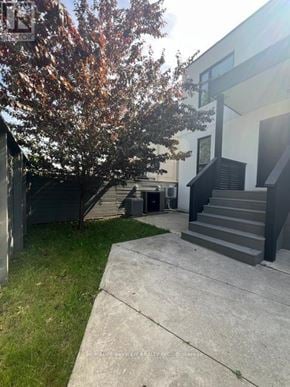 Toronto (East York) triplex for rent - A tree with orange leaves is in front of a white building.