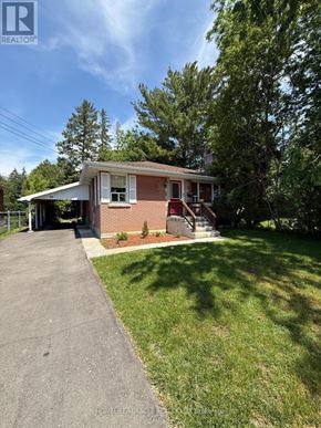 Belleville (Belleville Ward) apartment for rent - A house with a red brick exterior and a white roof is surrounded by greenery.