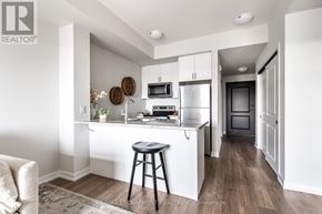 Hamilton (Stoney Creek) condo for rent - A modern kitchen with white cabinets and a wooden floor.
