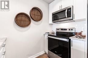Hamilton (Stoney Creek) condo for rent - A white kitchen with a black oven and a microwave above it.