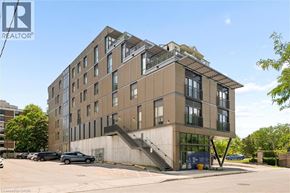 Kitchener condo for rent - A modern building with a parking lot in front.