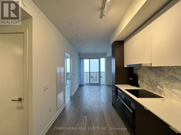 Toronto (Waterfront Communities) condo for rent - A spacious kitchen with dark wood floors and white countertops.