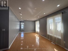 Brampton (Northwest Brampton) apartment for rent - A spacious room with wooden floors and a large window with white curtains.