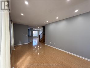 Brampton (Northwest Brampton) apartment for rent - A spacious room with wooden flooring and a staircase in the background.
