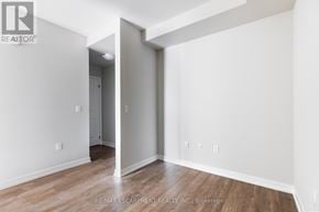 Hamilton (Stoney Creek) condo for rent - A room with white walls and wooden flooring, with a doorway leading to another room.