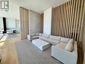 Mississauga (Cooksville) condo for rent - A modern living room with a grey sofa and a wooden panelled wall.