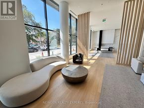 Mississauga (Cooksville) condo for rent - A modern waiting room with a curved white sofa and a wooden coffee table.