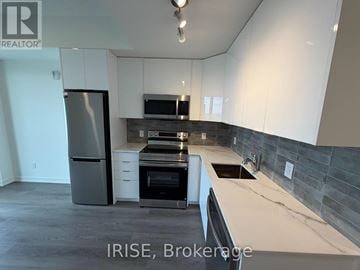 Brantford condo for rent - A kitchen with white cabinets and a black fridge.