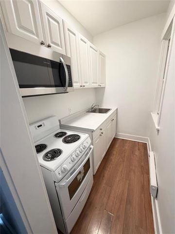 Winnipeg apartment for rent - A small kitchen with white appliances and wooden floors.