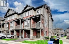Hamilton (Waterdown) townhouse for rent - A large, multi-story residential building with a balcony on the second floor.