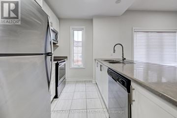 Hamilton (Waterdown) townhouse for rent - A kitchen with white cabinets and a stainless steel refrigerator.