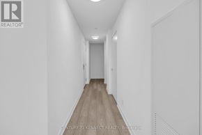 Toronto (South Parkdale) condo for rent - A long hallway with a light on the ceiling and a door at the end.