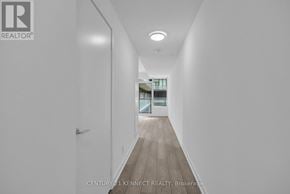 Toronto (South Parkdale) condo for rent - A long hallway with a door on the left and a window on the right.