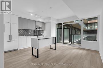 Toronto (South Parkdale) condo for rent - A modern kitchen with white cabinets and a black and white island.