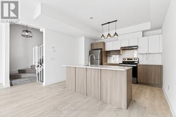 Burlington (Lasalle) townhouse for rent - A modern kitchen with white cabinets and a wooden island.