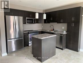 Niagara Falls (Forestview) townhouse for rent - A modern kitchen with a refrigerator, microwave, oven, and sink.