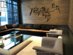 Toronto (Bay Street Corridor) condo for rent - A modern waiting area with a wooden wall and a glass table.