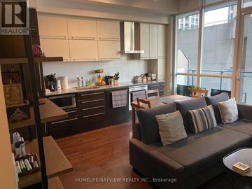 Toronto (Bay Street Corridor) condo for rent - A living room with a couch and a kitchen area in the background.