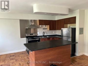 Toronto (Stonegate-Queensway) condo for rent - A kitchen with a black countertop and wooden cabinets.