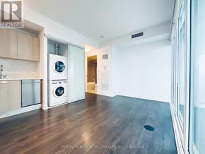 Toronto (Church-Yonge Corridor) condo for rent - A modern kitchen with wooden floors and a washing machine built into the cabinetry.