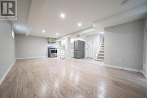 Oshawa (Central) duplex for rent - A spacious room with wooden flooring and a staircase in the background.