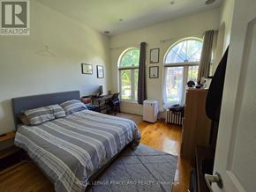 Toronto (Annex) multi-family for rent - A bedroom with a large bed and a window with a view of trees.