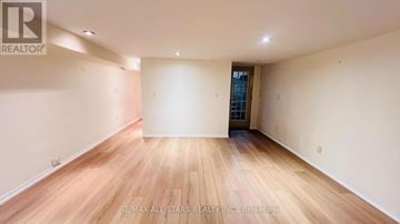 Toronto (Annex) townhouse for rent - A spacious room with wooden flooring and white walls.