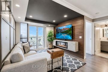 Markham (Unionville) condo for rent - A modern living room with a large grey sofa and a flat screen TV mounted on a wooden wall.
