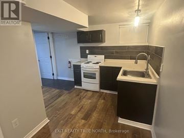 Barrie (Sanford) apartment for rent - A kitchen with a white stove top oven and a black counter top.