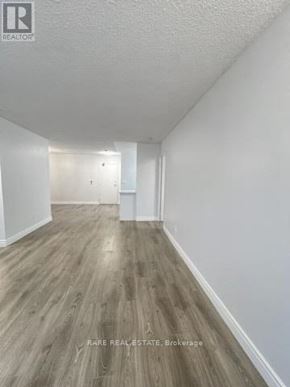 Mississauga (City Centre) condo for rent - A long, empty hallway with wood flooring and white walls.