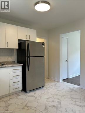 Dundas apartment for rent - A kitchen with a refrigerator, cabinets, and a marble floor.