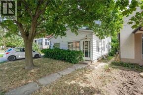 Guelph apartment for rent - A tree is in front of a house with a car parked in the driveway.
