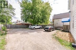 Guelph apartment for rent - A gravel driveway leads to a white car and a black car.