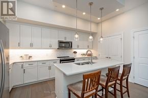 Guelph (Pineridge/Westminster Woods) condo for rent - A kitchen with white cabinets and a white island with two chairs.