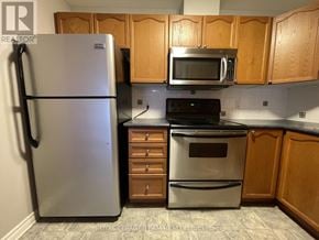 Ottawa townhouse for rent - A kitchen with a refrigerator, microwave, oven, and cabinets.