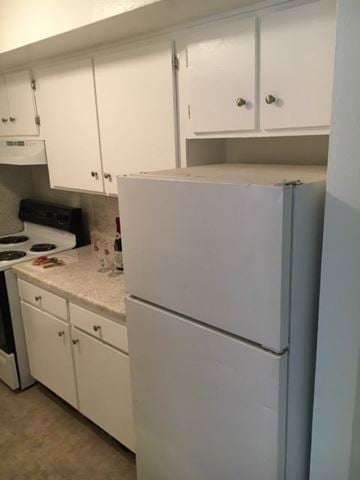 Oklahoma City apartment for rent - A white refrigerator in a kitchen with white cabinets.