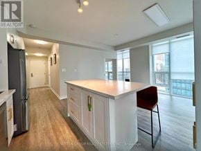Toronto (Waterfront Communities) condo for rent - A kitchen with white cabinets and a red chair.
