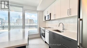 Toronto (University) condo for rent - A modern kitchen with a view of the cityscape outside the window.