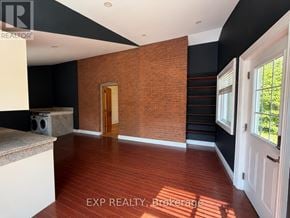 Orangeville multi-family for rent - A room with a wooden floor and a brick wall.