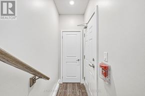 Burlington (Brant) townhouse for rent - A white door is in a hallway with a wooden staircase on the left.