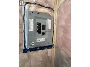 Maple Ridge apartment for rent - A wall-mounted electrical box with a grey exterior and a black interior is installed in a wall covered with insulation material.