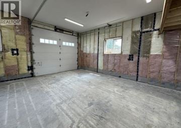 Maple Ridge apartment for rent - A spacious garage with a concrete floor and walls covered in insulation.