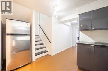 Kitchener apartment for rent - A modern kitchen with a stainless steel refrigerator and a staircase leading to the upper floor.