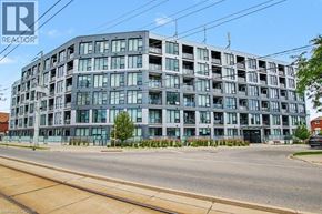 Kitchener condo for rent - A modern multi-story building with a glass facade is situated on a street corner.