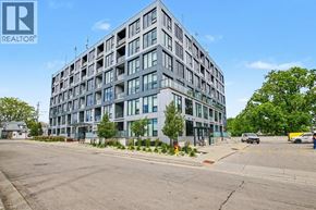 Kitchener condo for rent - A large, modern building with many windows is the main focus of the image.