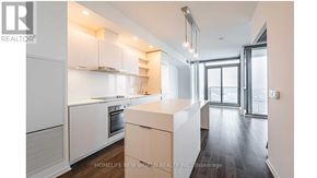 Toronto (Waterfront Communities) condo for rent - A modern kitchen with white cabinets and a wooden island.