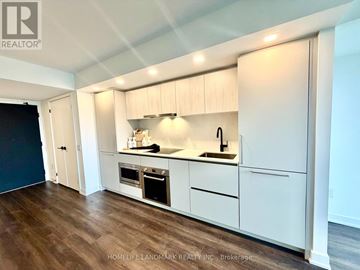 Toronto (North St. James Town) condo for rent - A kitchen with white cabinets and a wooden floor.