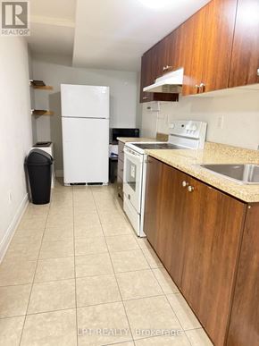 Mississauga (Churchill Meadows) apartment for rent - A kitchen with a white fridge, black trash can, and wooden cabinets.