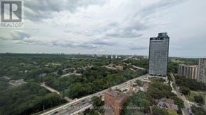 Toronto (North St. James Town) condo for rent - A tall building stands in the middle of a green landscape.